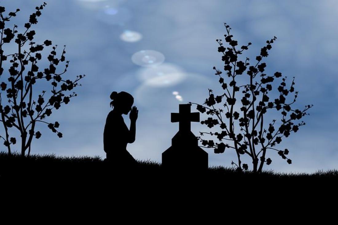 femme priant devant une tombe